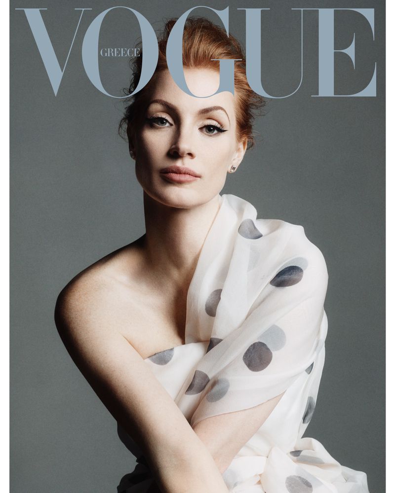 Close-up of Jessica Chastain on Vogue Greece cover, red hair, white polka dot shawl, light grey background, studio lighting.