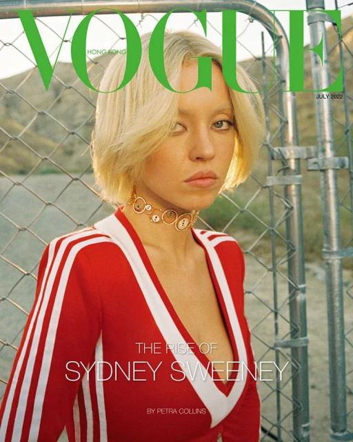 Vogue cover featuring a blonde woman wearing a red and white tracksuit-style top, with a mesh fence and mountains in background.