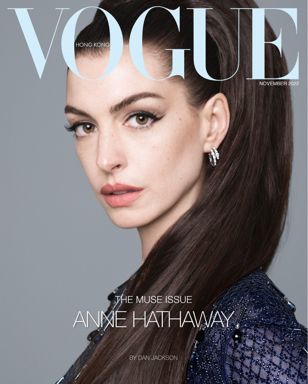 Vogue Hong Kong magazine cover featuring Anne Hathaway with dark hair pulled back, wearing jewelry and a shimmering top against grey.