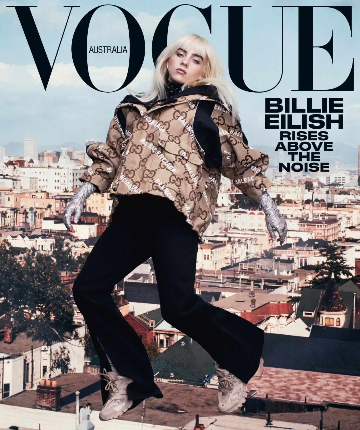Billie Eilish on Vogue Australia cover against an urban backdrop. Eilish wears a patterned jacket, dark pants, and light sneakers in the photo.