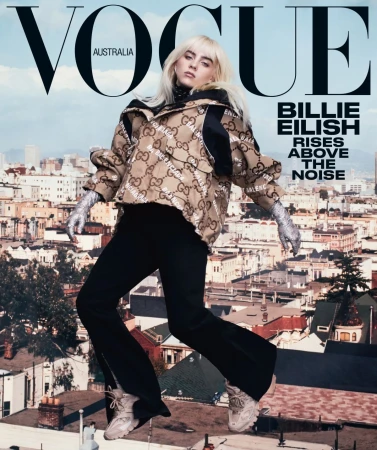 Billie Eilish on Vogue Australia cover against an urban backdrop. Eilish wears a patterned jacket, dark pants, and light sneakers in the photo.