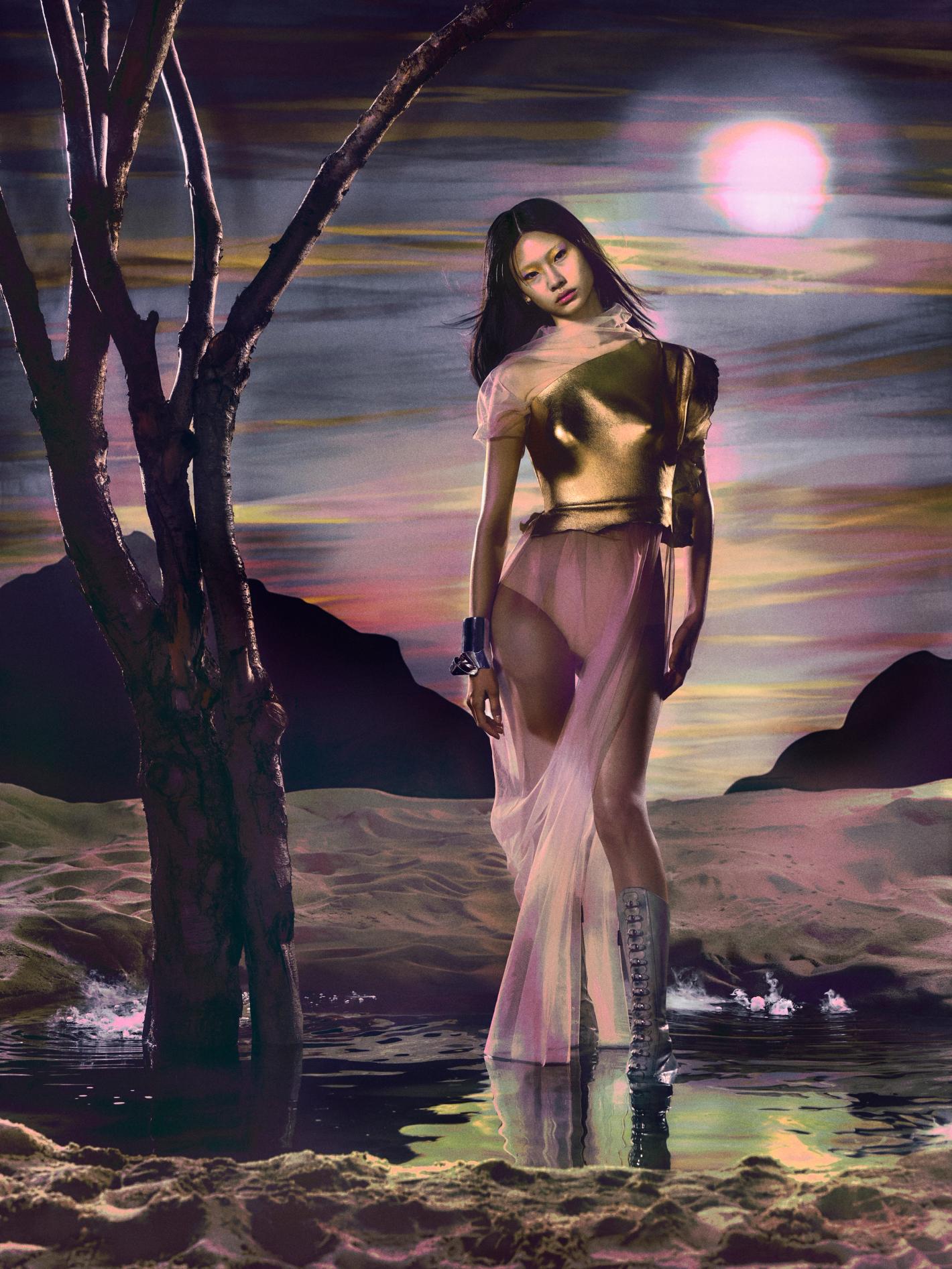 Artistic fashion photo of a woman in avant-garde gold top, sheer skirt, and boots, standing in a surreal waterscape under a hazy moon.