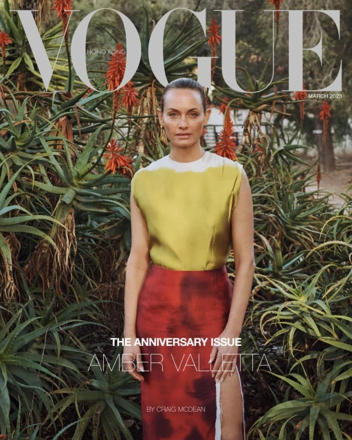 Vogue Hong Kong cover featuring model Amber Valletta in a yellow top and red skirt, posing against a backdrop of lush greenery.