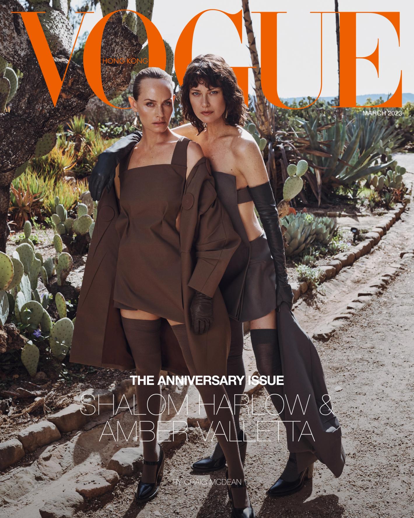 Two women, Shalom Harlow and Amber Valletta, pose in brown outfits against a desert backdrop for a Vogue Hong Kong magazine cover.
