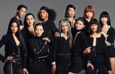 Group of diverse female models in coordinated black outfits posing against a neutral grey studio background
