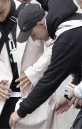 Group of young men wearing streetwear apparel including a light pink coat and black hoodie