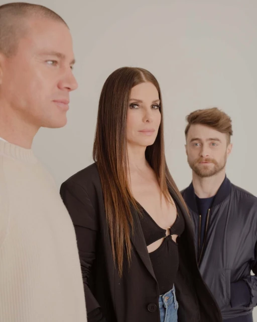 Promotional photo of Channing Tatum, Sandra Bullock, and Daniel Radcliffe in front of a plain background. Radcliffe wears a bomber jacket.