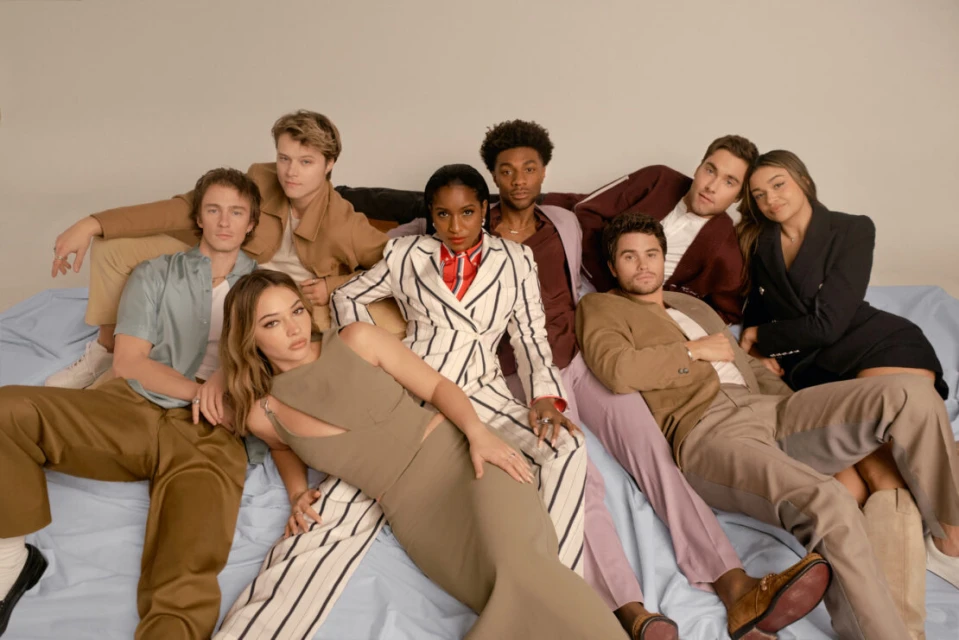 Group studio portrait of eight young adult diverse people, posing, wearing fashionable outfits in earth tones, horizontal orientation.