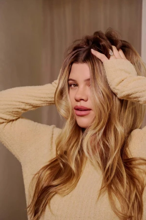 Portrait of a blonde woman wearing a textured sweater with her hands in her hair, photographed by Amy Harrity.