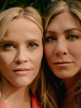 Close-up portrait of actresses Reese Witherspoon and Jennifer Aniston, side-by-side, showcasing their similar hair and eye color outdoors.