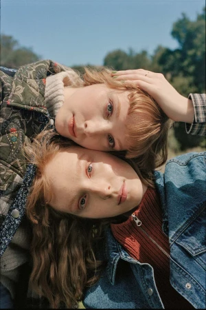 Two young women with reddish hair posing outdoors together against a clear blue sky background captured from above