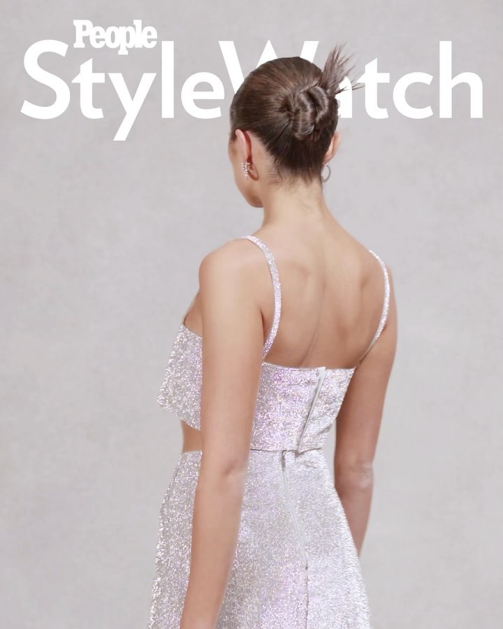 Back view of a woman with her hair up wearing a sparkly two-piece outfit, featuring 'People StyleWatch' logo; light neutral backdrop.