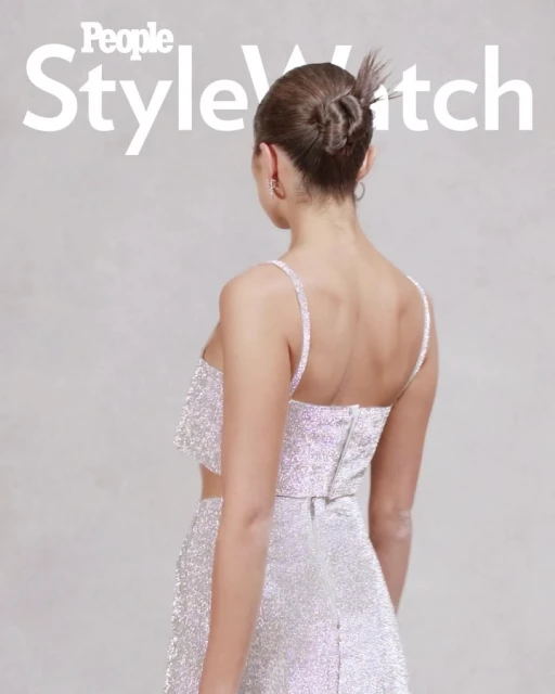 Back view of a woman with her hair up wearing a sparkly two-piece outfit, featuring 'People StyleWatch' logo; light neutral backdrop.