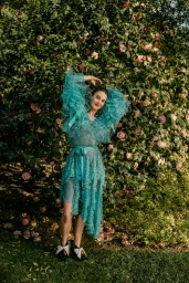 Woman in a ruffled turquoise tulle dress posing in front of a dense flowering rose bush in Los Angeles by photographer Amy Harrity.
