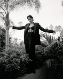 Model in black suit jacket and trousers posing amidst palm trees in Los Angeles by photographer Amy Harrity