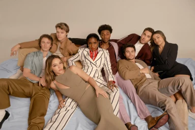 Group portrait of eight diverse young adults posing together casually on a light studio background photographed by Amy Harrity.