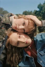 Two young women with reddish hair posing outdoors together against a clear blue sky background captured from above