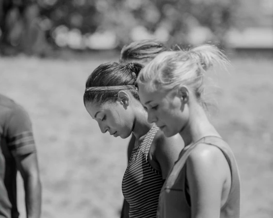 Monochrome close-up portrait of three athletes with heads bowed outdoors
