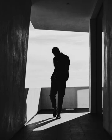 Silhouette of a man standing on a balcony framed by architectural walls in a monochrome portrait by Clayton Cotterell