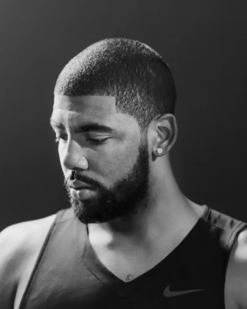 Portrait of Kyrie Irving wearing a dark tank top against a dark background, photographed by Clayton Cotterell