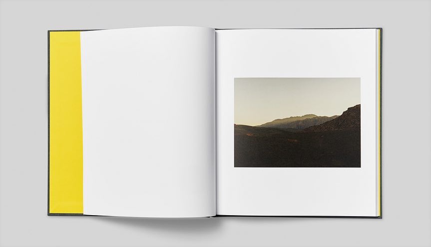 Open book featuring a photograph of a mountain range on the right page, with a bright yellow endpaper on the left.