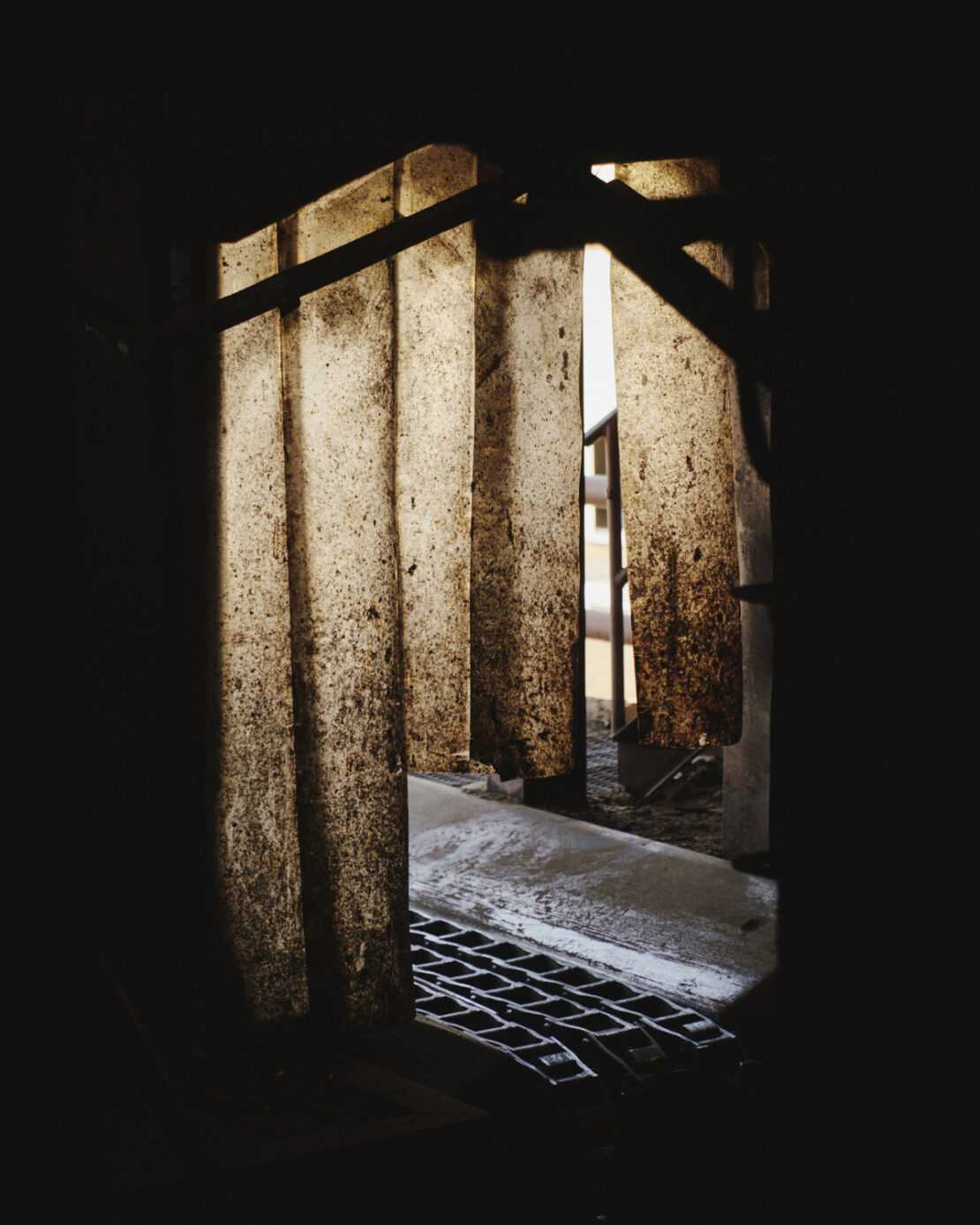 Textured translucent plastic strip curtains hanging in a dark industrial doorway