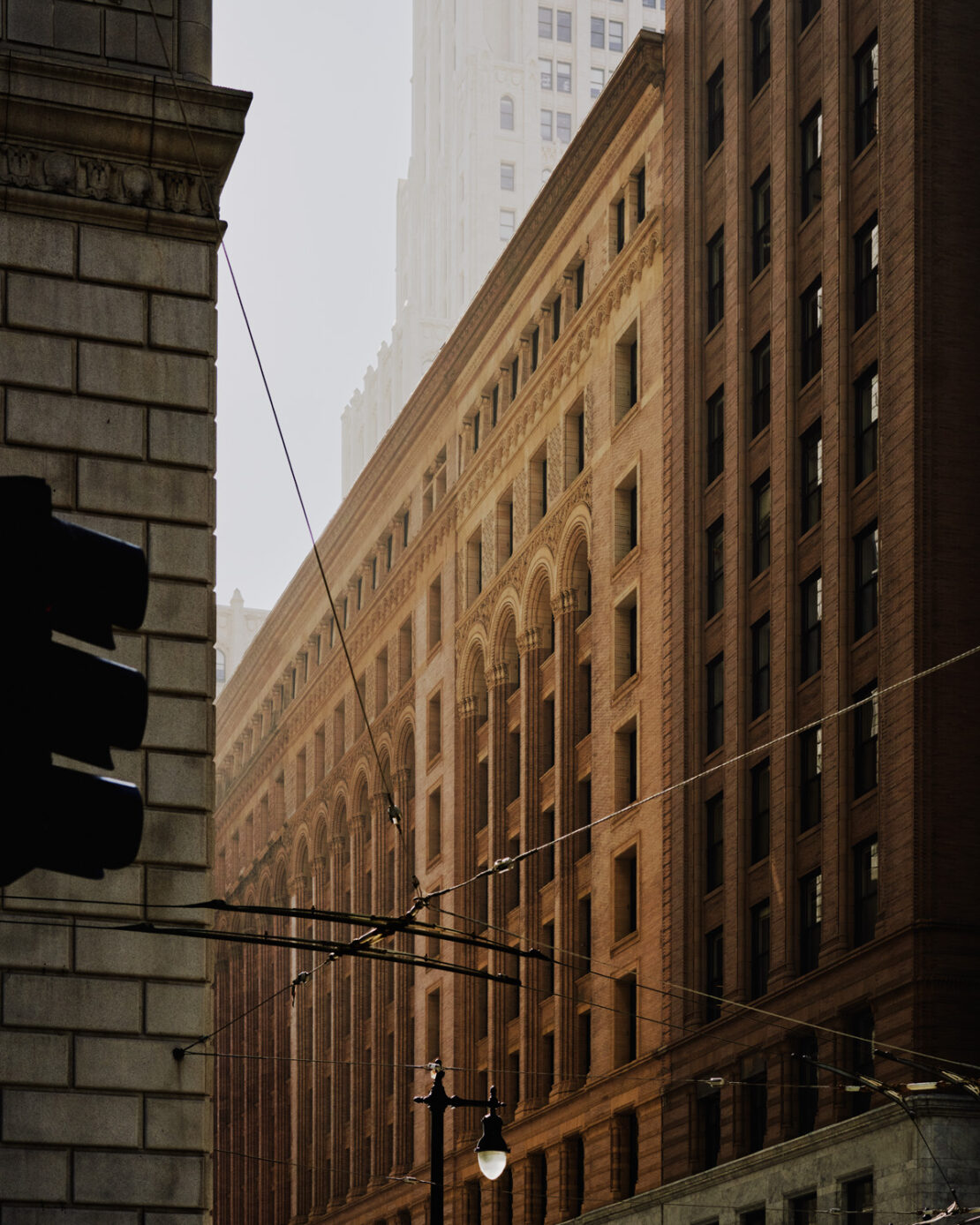 Cityscape featuring the architectural facade of a brownstone building on a misty day, with wires stretching across the urban scene.