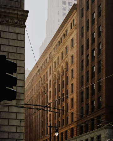 Cityscape featuring the architectural facade of a brownstone building on a misty day, with wires stretching across the urban scene.