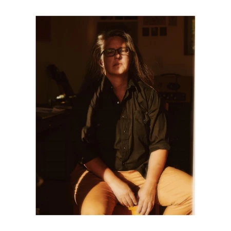 Portrait of a woman wearing glasses and a dark shirt seated in an interior room