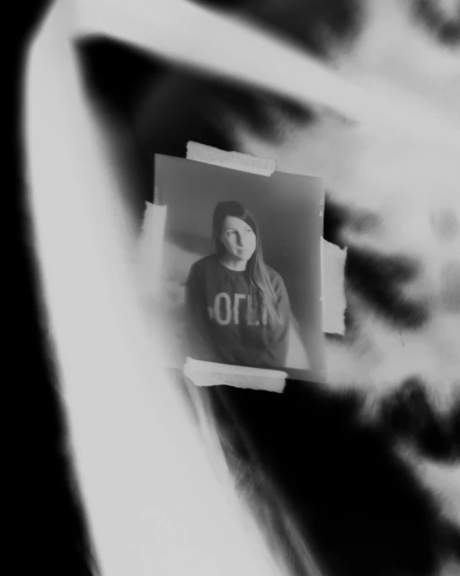 Monochrome portrait of a woman with long hair, taped to a wall with abstract shadows, creating an artistic and slightly blurred effect.