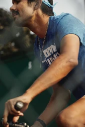 Man riding a bicycle wearing a blue t-shirt and light blue bandana photographed by Clayton Cotterell