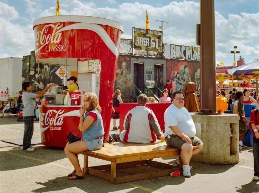 Outdoor shot featuring a Coca-Cola-themed food stand with customers and an 'Area 51' attraction, capturing a unique blend of commercial and themed environments.
