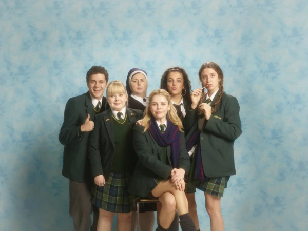 Group portrait of six individuals in school uniforms against a blue backdrop, capturing a playful, editorial style reminiscent of a school photo.