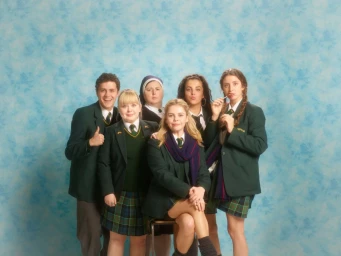 Group of six people in school uniforms posing in front of a blue mottled backdrop by photographer Dan Burn-forti.