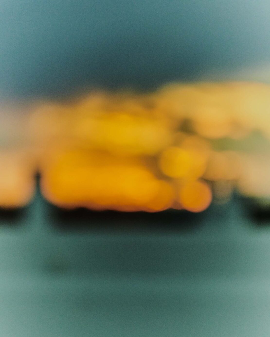 Abstract, blurry background in shades of blue, green, and orange, with a horizontal bokeh effect, creating a serene ambiance.