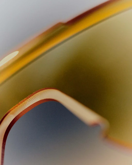 Close-up of the orange-rimmed lenses of sunglasses, showing the curve of the frames and the reflection of light on the surface.