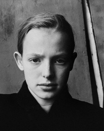 Close-up black and white portrait of a young person wearing a dark collared shirt against a textured background.