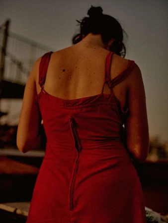 Rear view of a woman wearing a red dress with a visible zipper down the back against an outdoor background