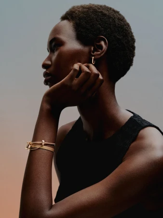 Profile portrait of a Black woman wearing gold hoop earrings and a bracelet, captured in soft lighting by Daniel Benson in London.