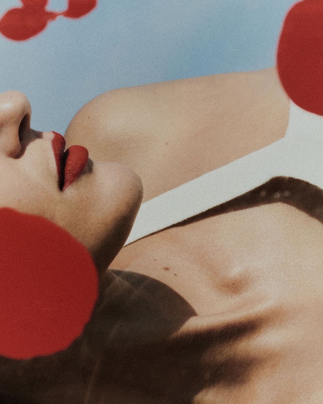Adult woman's face and body is partially covered by red circles, creating an abstract and artistic beauty or fashion image.