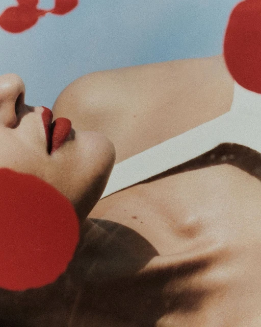 Adult woman's face and body is partially covered by red circles, creating an abstract and artistic beauty or fashion image.