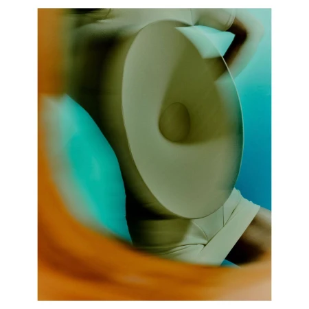 Abstract fashion shot featuring a person in a tan outfit behind a circular object with blurred orange and blue background.
