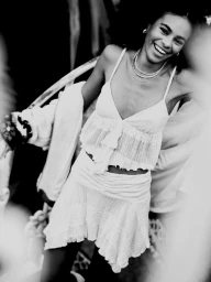 Black and white portrait of a smiling young woman wearing a textured top and ruffled skirt by Daniel Benson