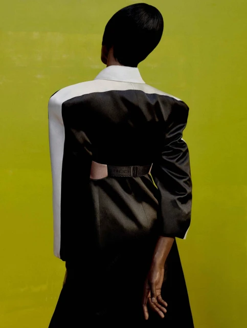 Back view of a Black model in a black and white dress against a yellow background. Fashion editorial style photograph.