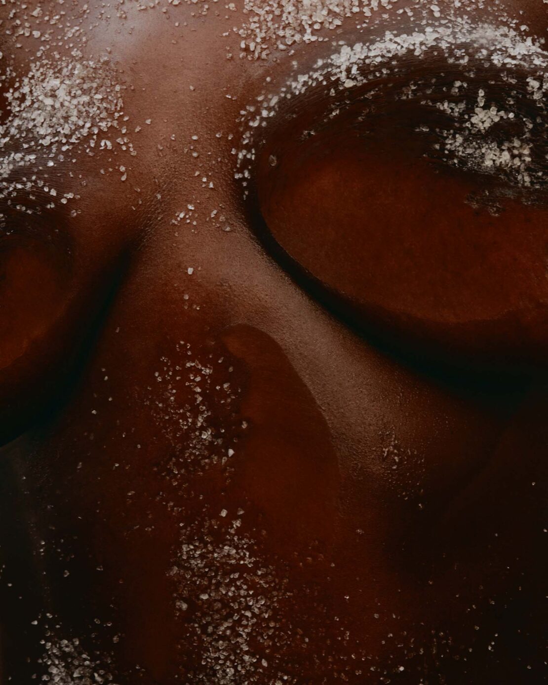 Closeup of a person's skin with a sprinkling of white crystals on top, highlighting the texture and tones.