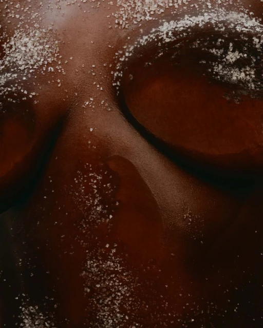 Closeup of a person's skin with a sprinkling of white crystals on top, highlighting the texture and tones.