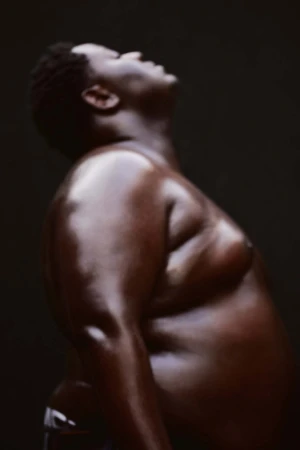 Profile portrait of a Black man with head tilted back against a dark background