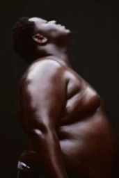 Profile portrait of a Black man with head tilted back against a dark background