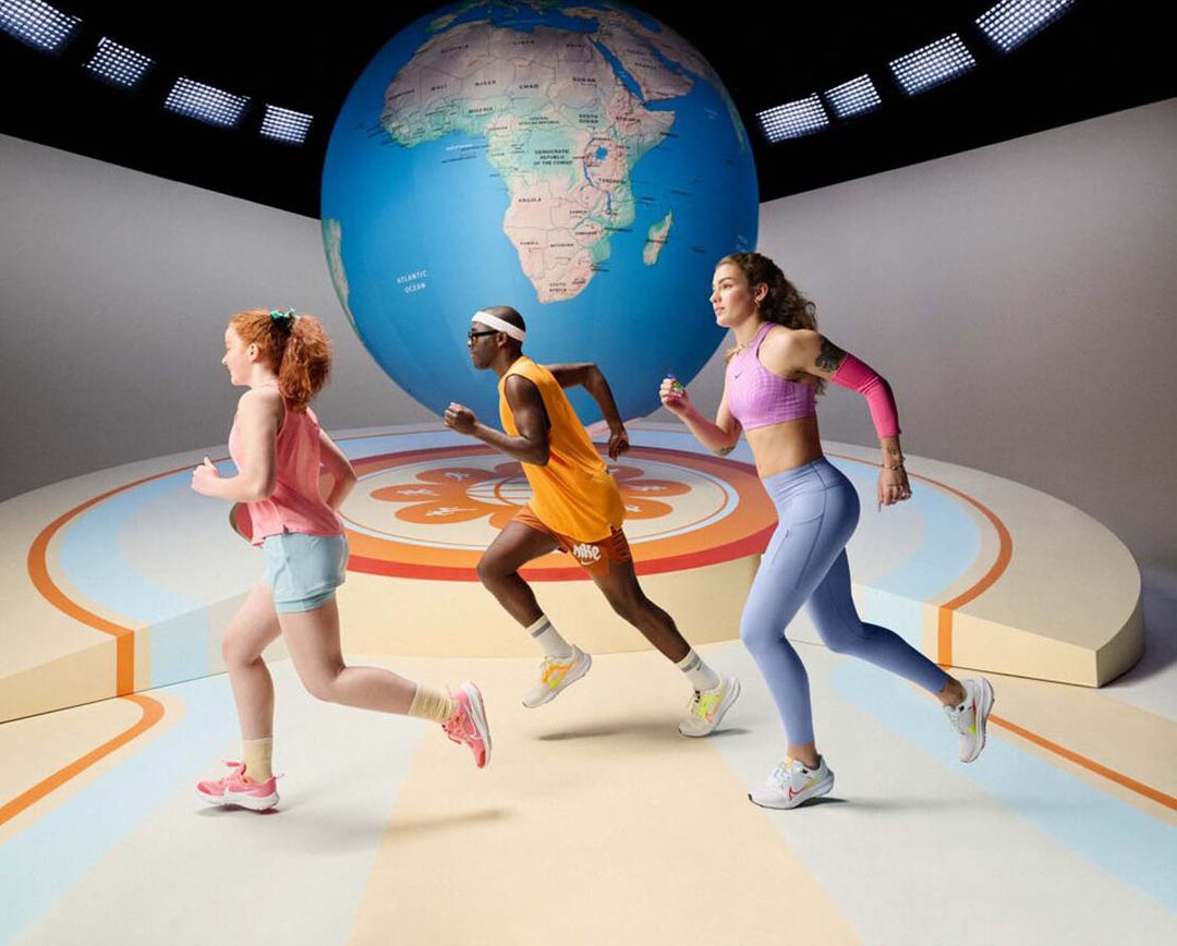 Three runners, two women and one man, are in motion against a backdrop featuring a large globe and studio lighting.