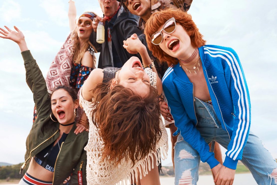 A vibrant group of young adult friends outdoors, laughing and celebrating under daylight, captured with natural lighting.